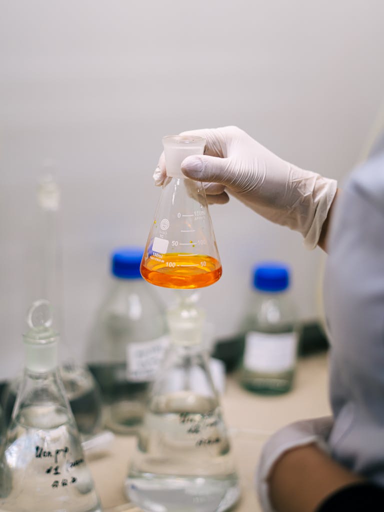 Laboratory scene with a scientist examining orange liquid in an Erlenmeyer flask, showcasing research and experimentation.